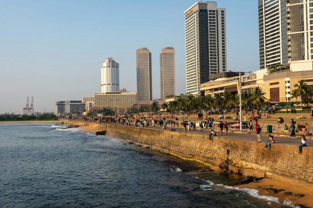 Galle Face Green's sea wall and promenade in evening light, with the Shangri-La and World Trade Center towers behind