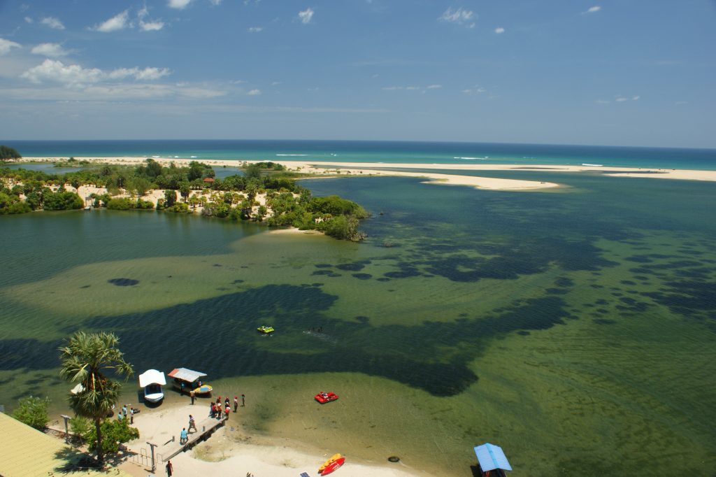 View from above over the shallow green lagoon mouth at Palameenmadu, with sandbanks, small boats and the sea beyond