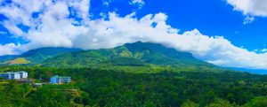Forested hills and a cloud-capped mountain above Belihuloya, with Sabaragamuwa University buildings among the trees in the foreground