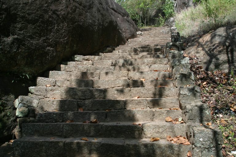 Worn granite steps of the ancient stairway climbing the Dambadeniya rock beside a dark boulder