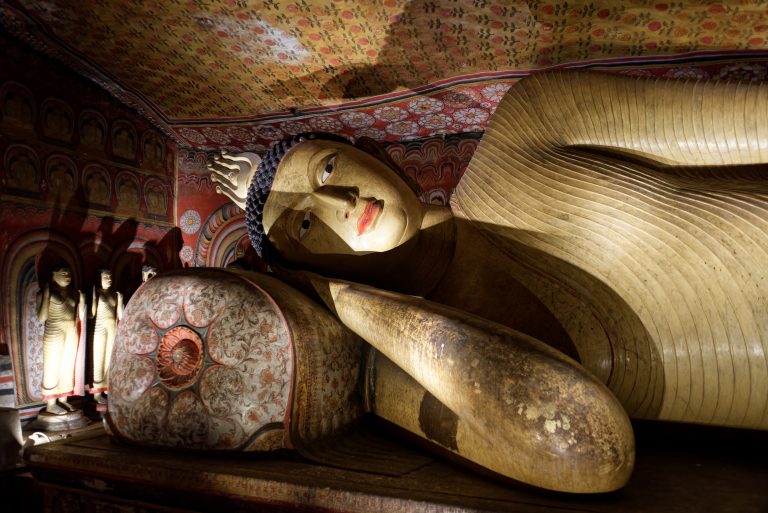 The head of the reclining Buddha on a painted pillow, under a ceiling covered in floral patterns