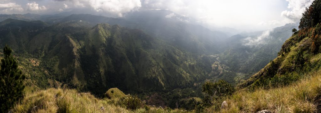 Panorama of the Ella Gap, a deep green valley between steep forested ridges, with cloud and haze over the hills