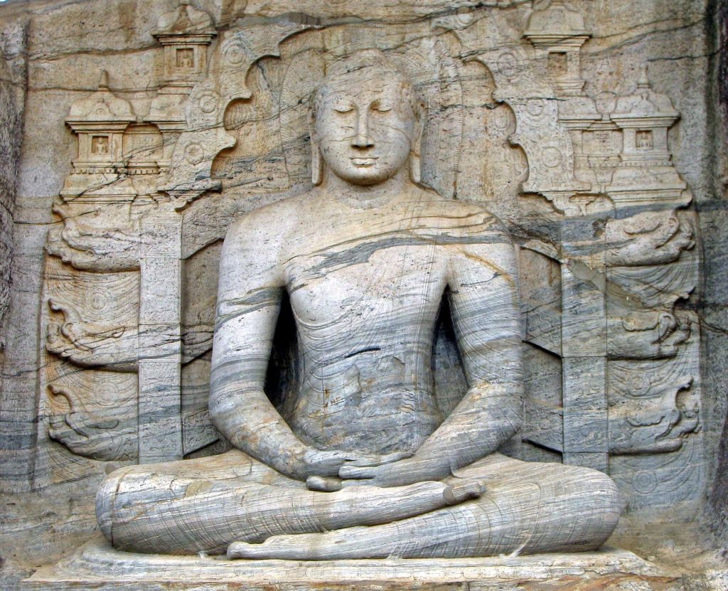 The large seated Buddha at Gal Vihara in meditation pose, with carved shrines and panels behind it