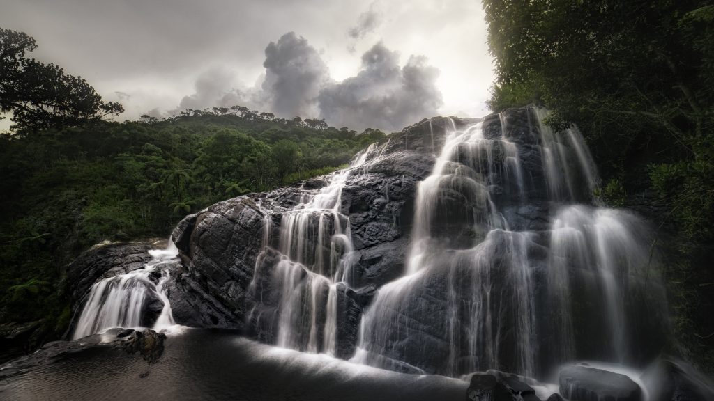 Baker's Falls spilling in several streams over dark rock, with forest on both sides
