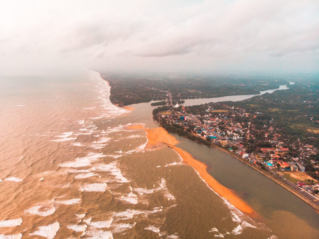 Aerial view of Kalutara where the Kalu Ganga meets the sea, with a long sand spit, the lagoon, the town and the white stupa by the bridge