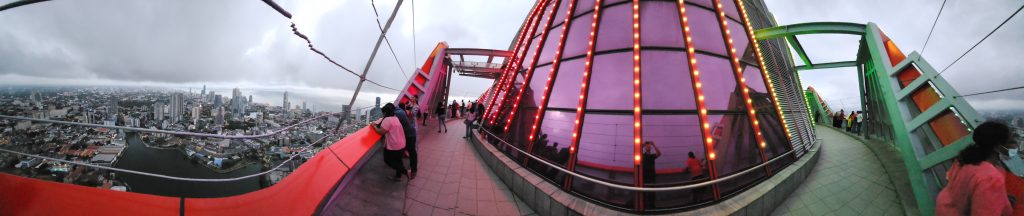 Panorama of the Lotus Tower observation deck with visitors walking round the lit lotus-bud top and Colombo's rooftops below