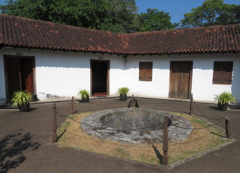 Courtyard of the Star Fort in Matara: low whitewashed buildings with red clay-tiled roofs and wooden doors around a round stone well