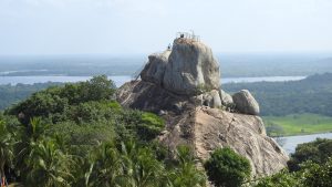 Aradhana Gala, a granite rock outcrop with railings and steps to its summit, above trees with lakes and plains beyond