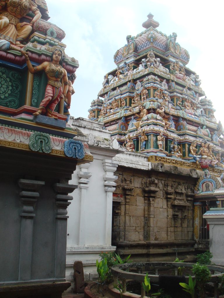 The painted tower of the Siva temple at Munneswaram, covered in figures of deities, rising above the old stone walls of the sanctum