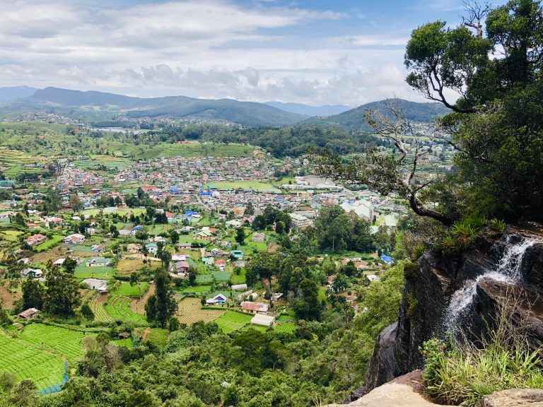View from the rocks beside Lover's Leap over the roofs of Nuwara Eliya and surrounding tea and vegetable terraces, with a small cascade on the right