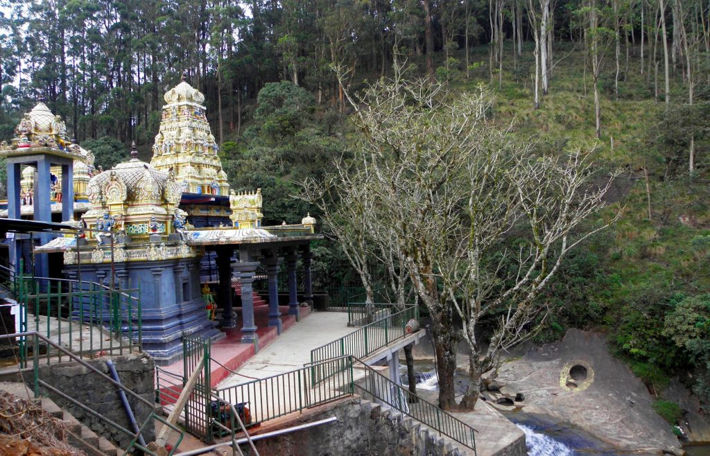 The temple shrine and walkway above a stream, with rounded hollows in the rock slab on the far bank