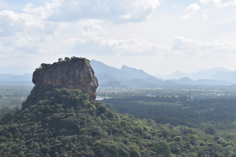 Sigiriya rock rising above the forest, seen from Pidurangala, with mountains on the horizon