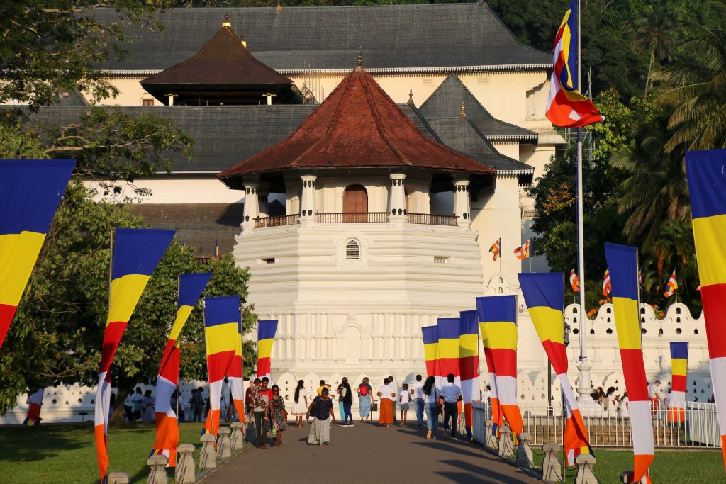 The octagonal Paththirippuwa of the Temple of the Tooth at the end of a path lined with Buddhist flags