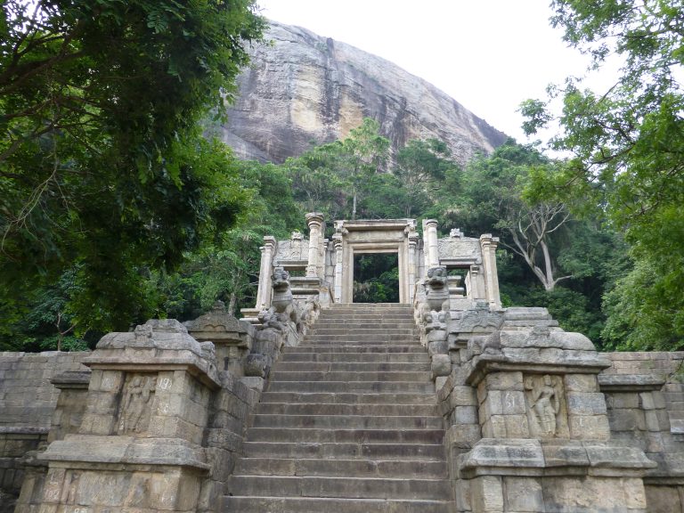 The carved stone stairway at Yapahuwa climbing between stone lions to an ornamental gateway, with the bare granite rock rising behind